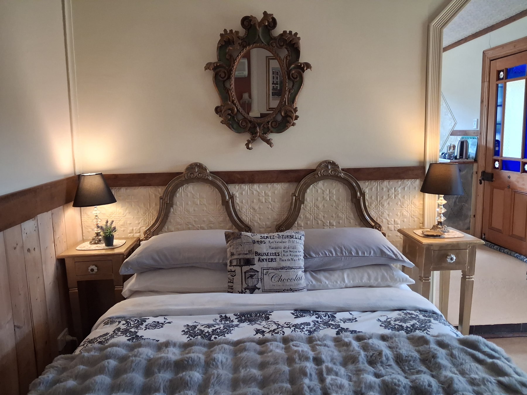 Queen bed with ornate headboard in La Petite Maison